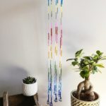 Glitzerndes Windspiel aus Holzscheibe und Perlen